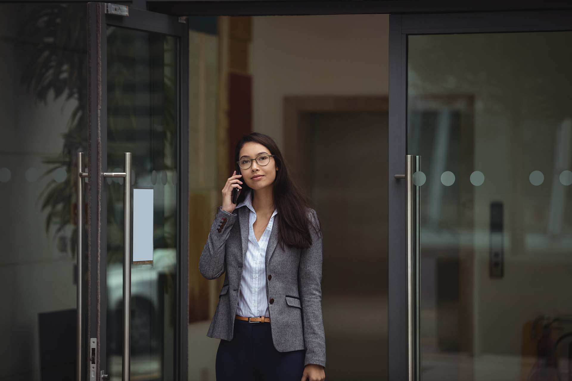 Businesswoman talking on mobile phone outside office building